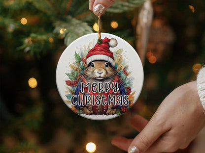 Round holiday ornament with woodland rabbit artwork, winter berries, golden foliage, and Merry Christmas lettering.