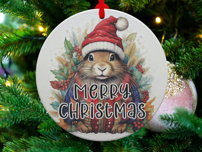 Woodland bunny ornament featuring a Santa hat, red berries, pine sprigs, and nature-inspired holiday artwork.