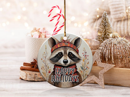 Happy Holidays ornament featuring a woodland raccoon framed by delicate berry branches and botanical foliage.