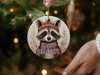 Watercolour raccoon ornament wearing a red plaid headband with berries and a cosy red winter scarf.
