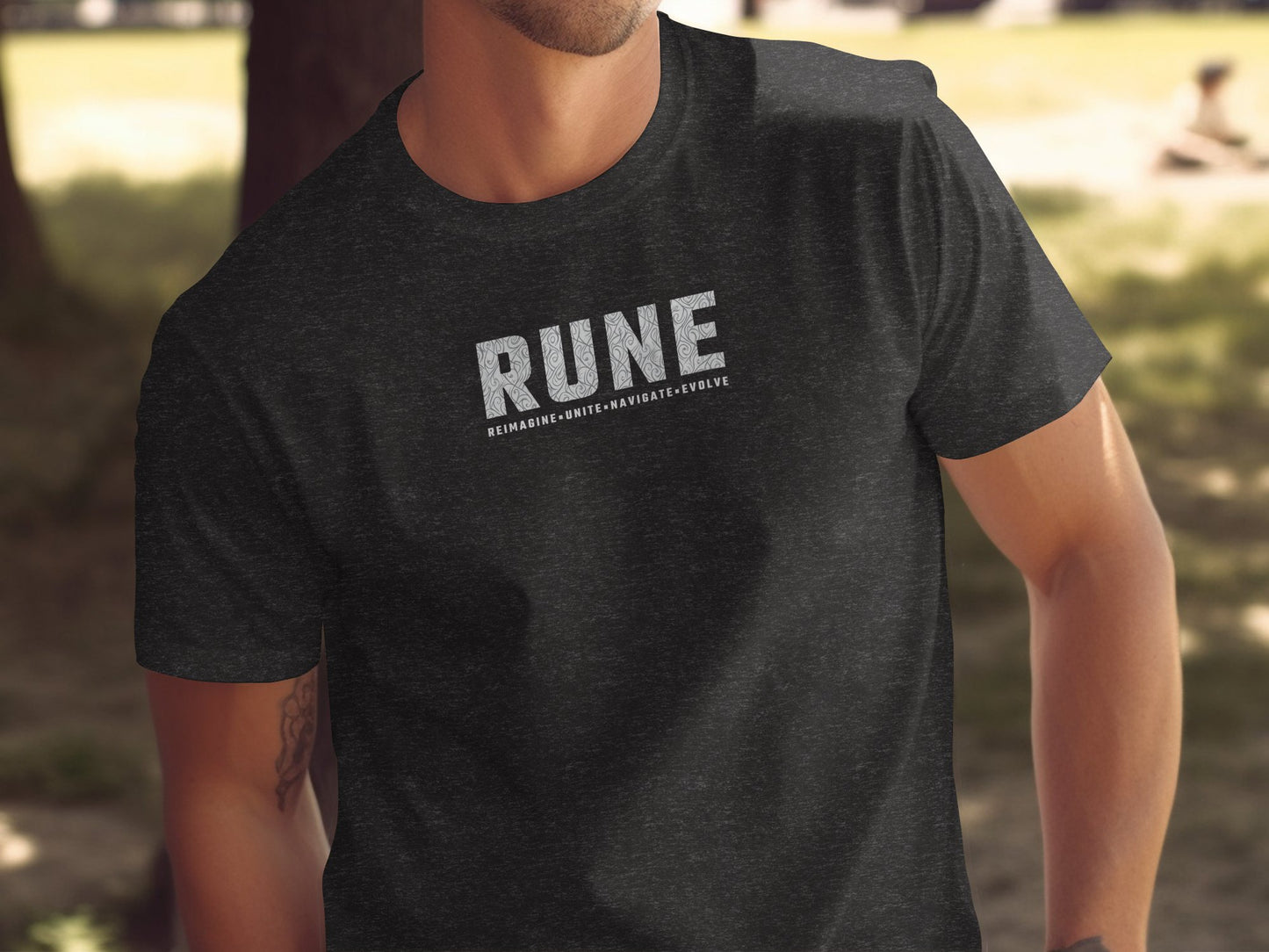 Dark heather grey RUNE t‑shirt with centre‑chest textured RUNE lettering and structured Reimagine, Unite, Navigate, Evolve tagline.