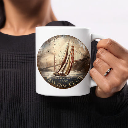 11oz San Francisco Sailing Club ceramic mug held in hand, showing warm cream sails, terracotta-red artwork and vintage maritime detailing.