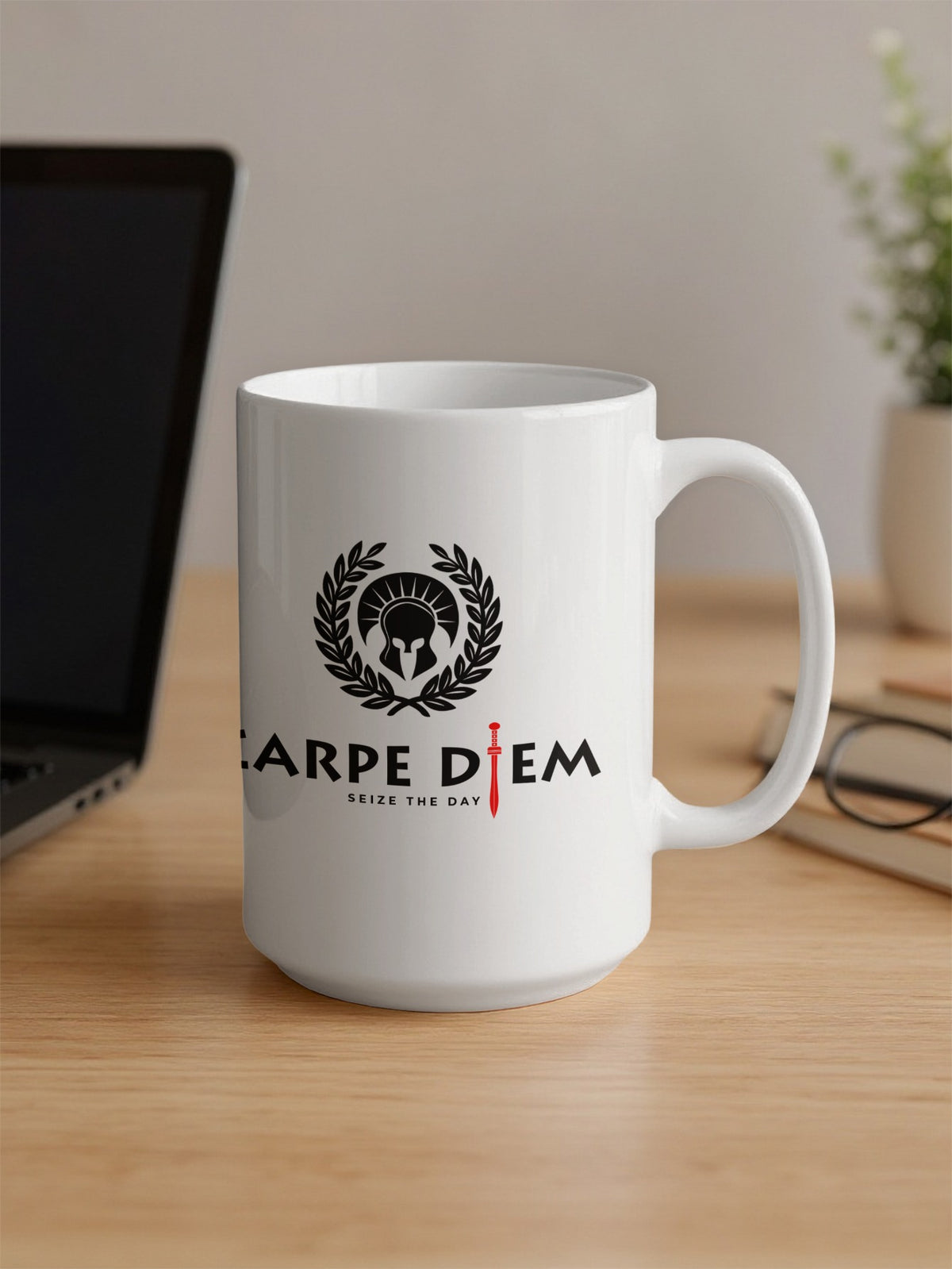 White ceramic 15oz Seize the Day Mug in an office setting, showing the laurel wreath, red gladius and Roman-style black typography.