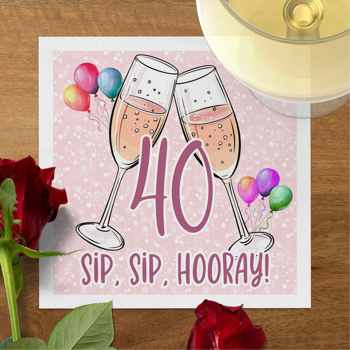 Custom milestone birthday cocktail napkin with rosé flutes, bright party balloons and bold personalised age typography.