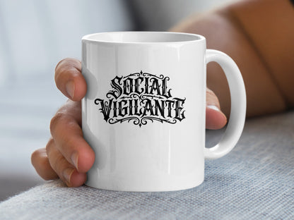 Handheld 11oz Social Vigilante Mug showing dramatic blackletter typography and intricate ornamental detailing.