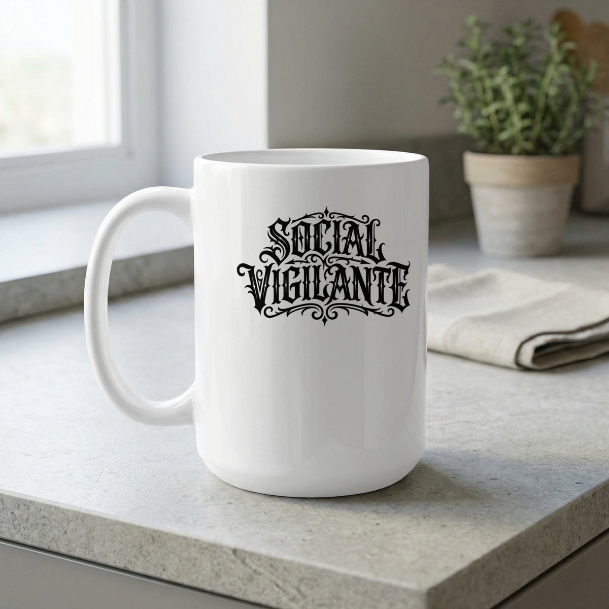 15oz Social Vigilante Mug on a kitchen counter featuring ornate gothic typography, symmetrical flourishes and framed artwork.
