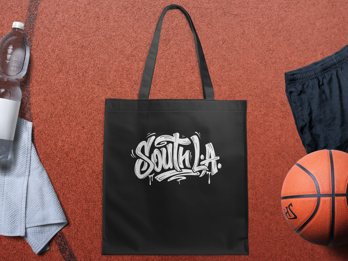 Black South L.A. canvas tote bag featuring bold white graffiti lettering, dark grey shadowing and expressive hand-drawn details.