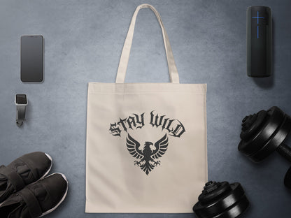 Stay Wild Heraldic Eagle Tote Bag featuring blackletter typography above a detailed black eagle crest on natural canvas.