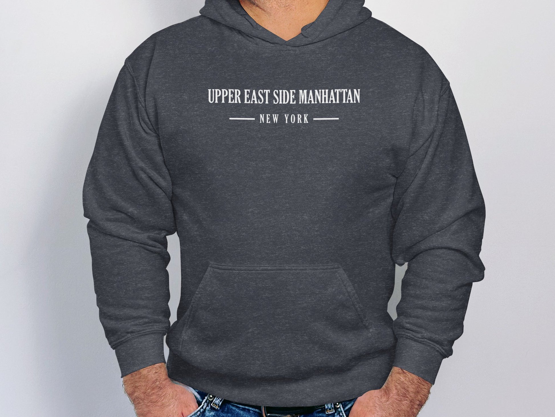 Dark heather grey Upper East Side Manhattan hoodie featuring monochrome serif text and minimalist urban chest layout.