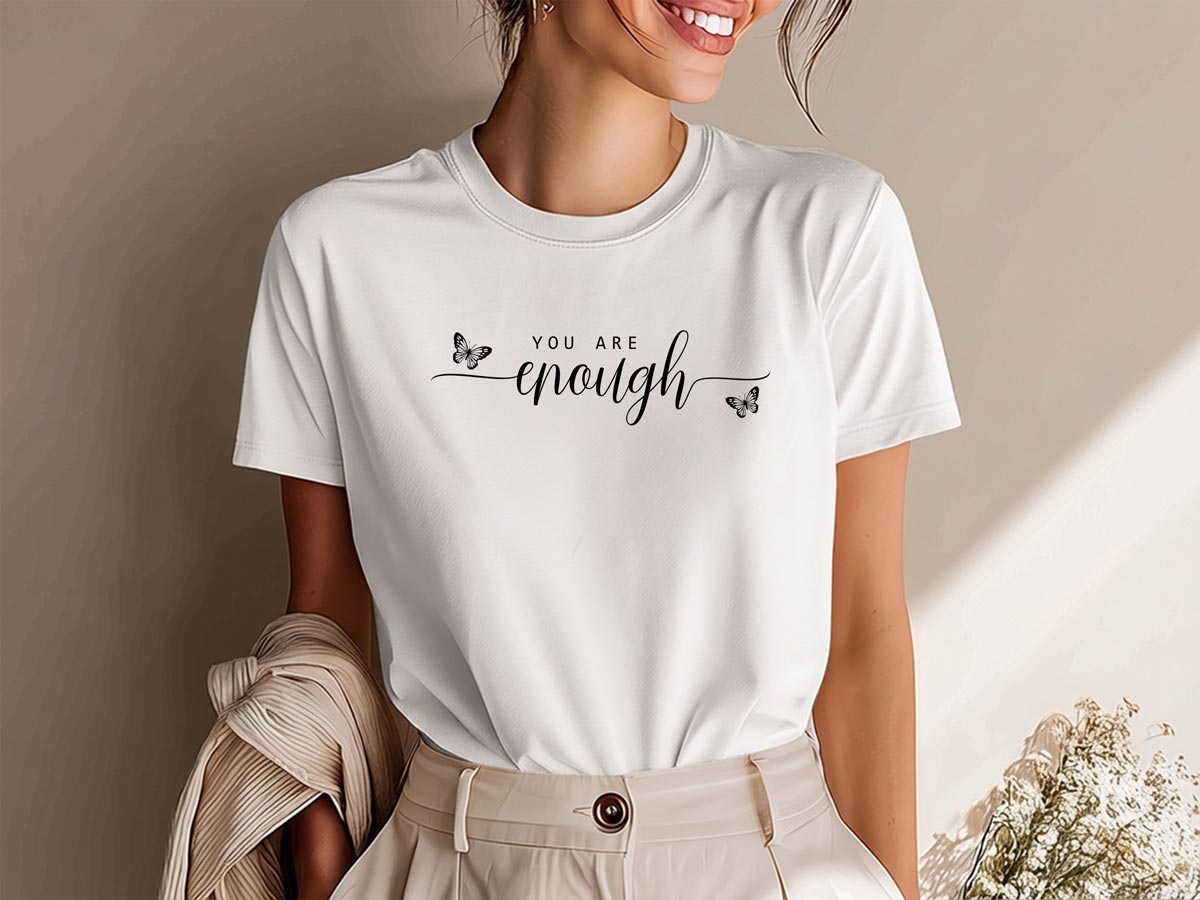 Woman wearing white crew neck graphic t-shirt featuring flowing black calligraphy across the chest with two butterfly accents.