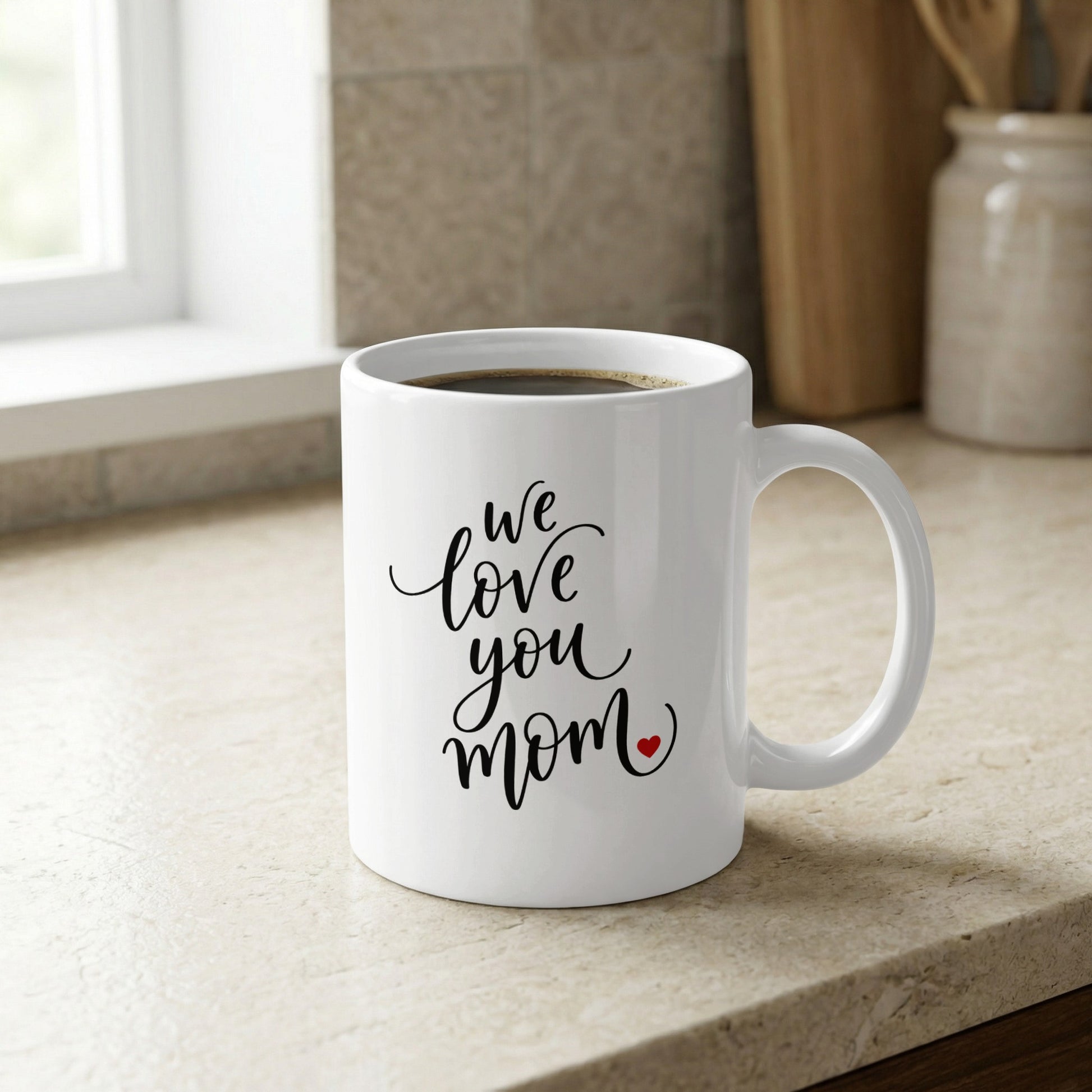 We Love You Mom 11oz ceramic mug on kitchen counter, a stylish and practical gift for moms who love coffee.